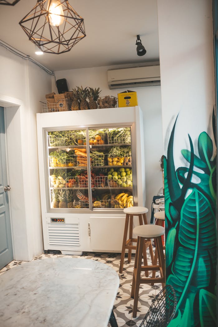 Contemporary kitchen interior featuring a glass refrigerator filled with fruits and stylish decor.